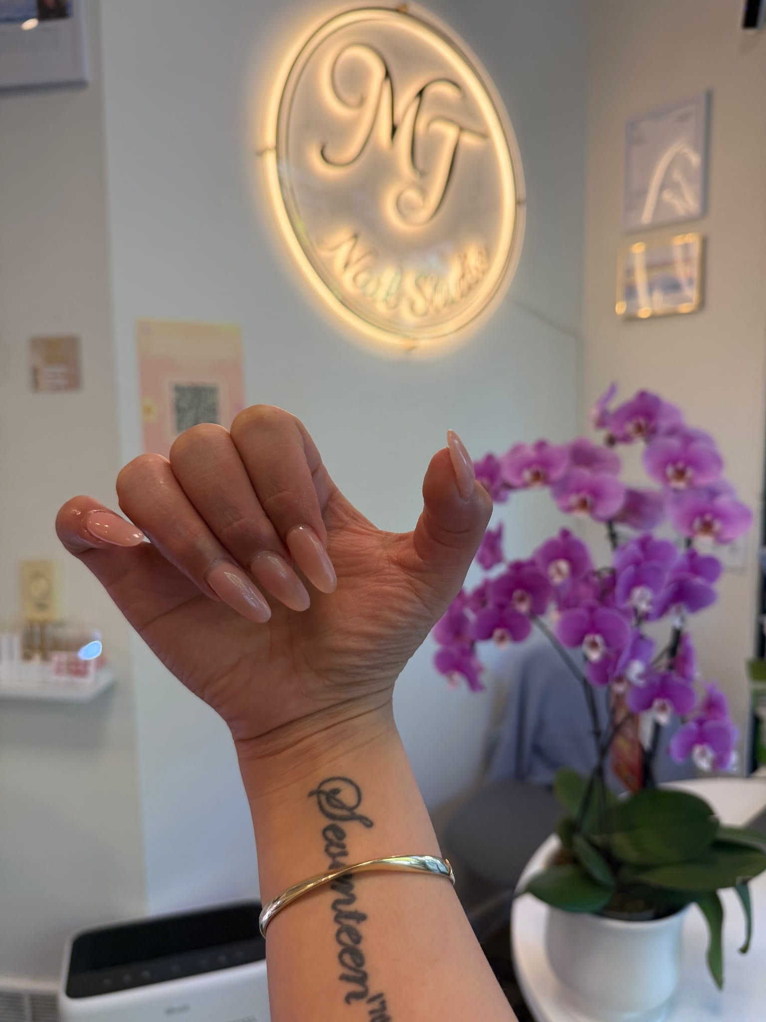 Hand with long almond-shaped natural acrylic nails at MT Nail Studio