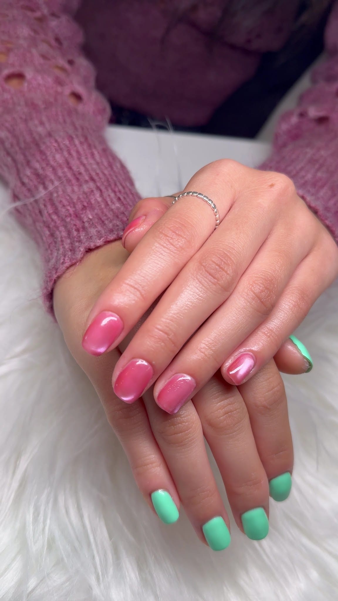 Hands with glossy pink and mint green gel polish on short square nails