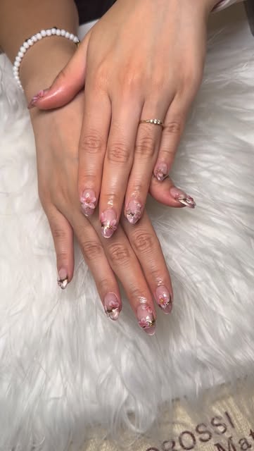 Two hands with pink floral nail art designs on almond-shaped nails