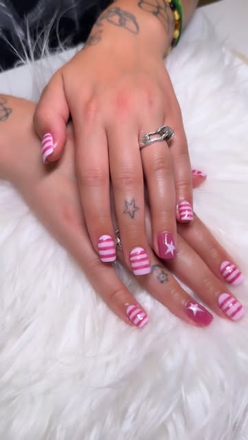 Hands with pink and white striped nail art featuring star designs