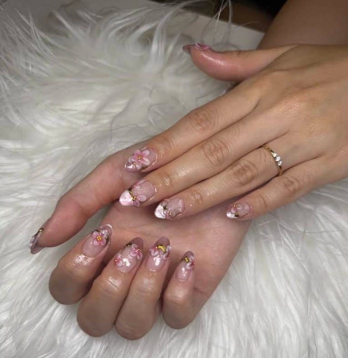 Two hands with long almond nails featuring 3D pink floral nail art