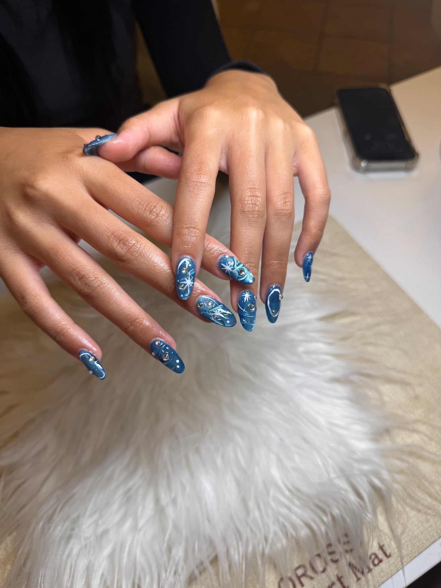 Long almond acrylic nails with blue nail art, stars, and rhinestones