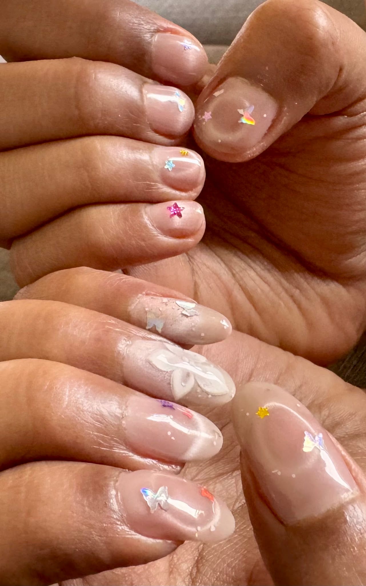 Hands and feet with sheer nails decorated with butterfly and star charms